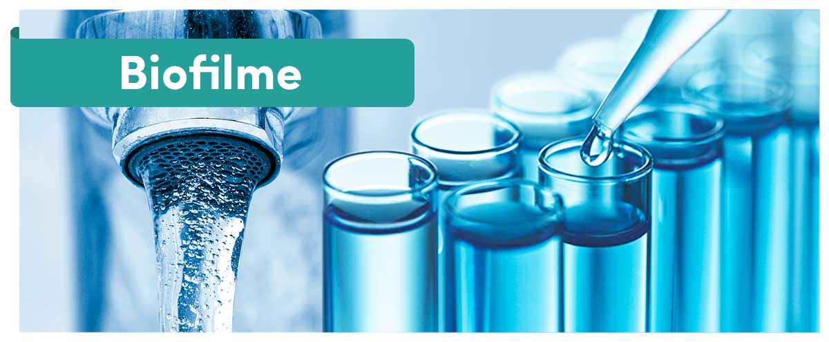 Biofilme im türkisen Textbalken vor Wasserhahn und blau gefüllten Reagenzgläsern