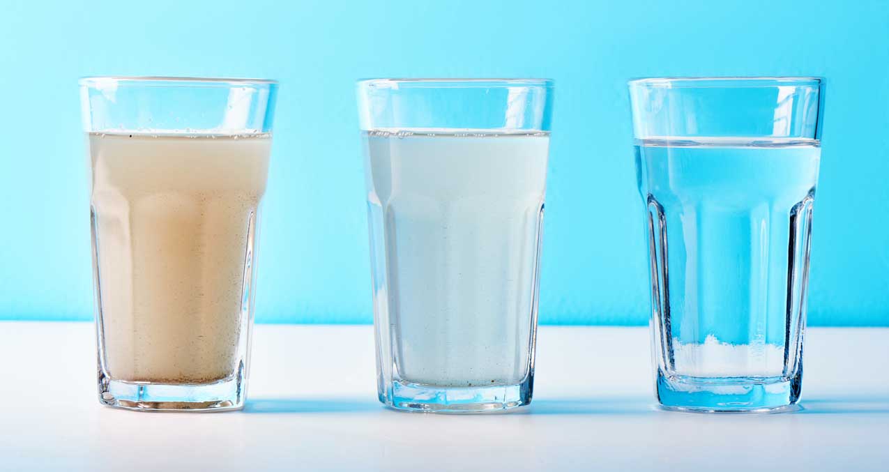 Drei Gläser im Vergleich: bräunlich trübes, milchig weißes und klares Wasser nebeneinander
