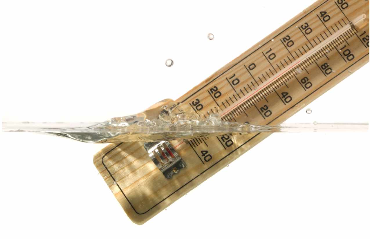 Analoges Holzthermometer mit doppelter Skala, halb in klares Wasser eingetaucht, Luftblasen darum