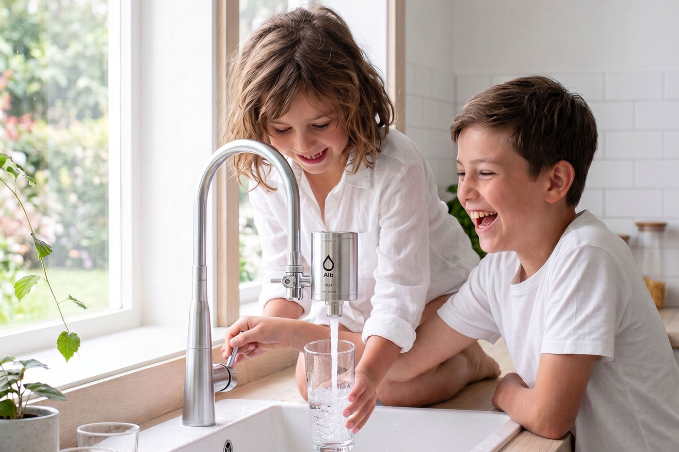 Zwei lachende Kinder zapfen gefiltertes Wasser mit dem Alb Wasserhahnfilter direkt am Wasserhahn