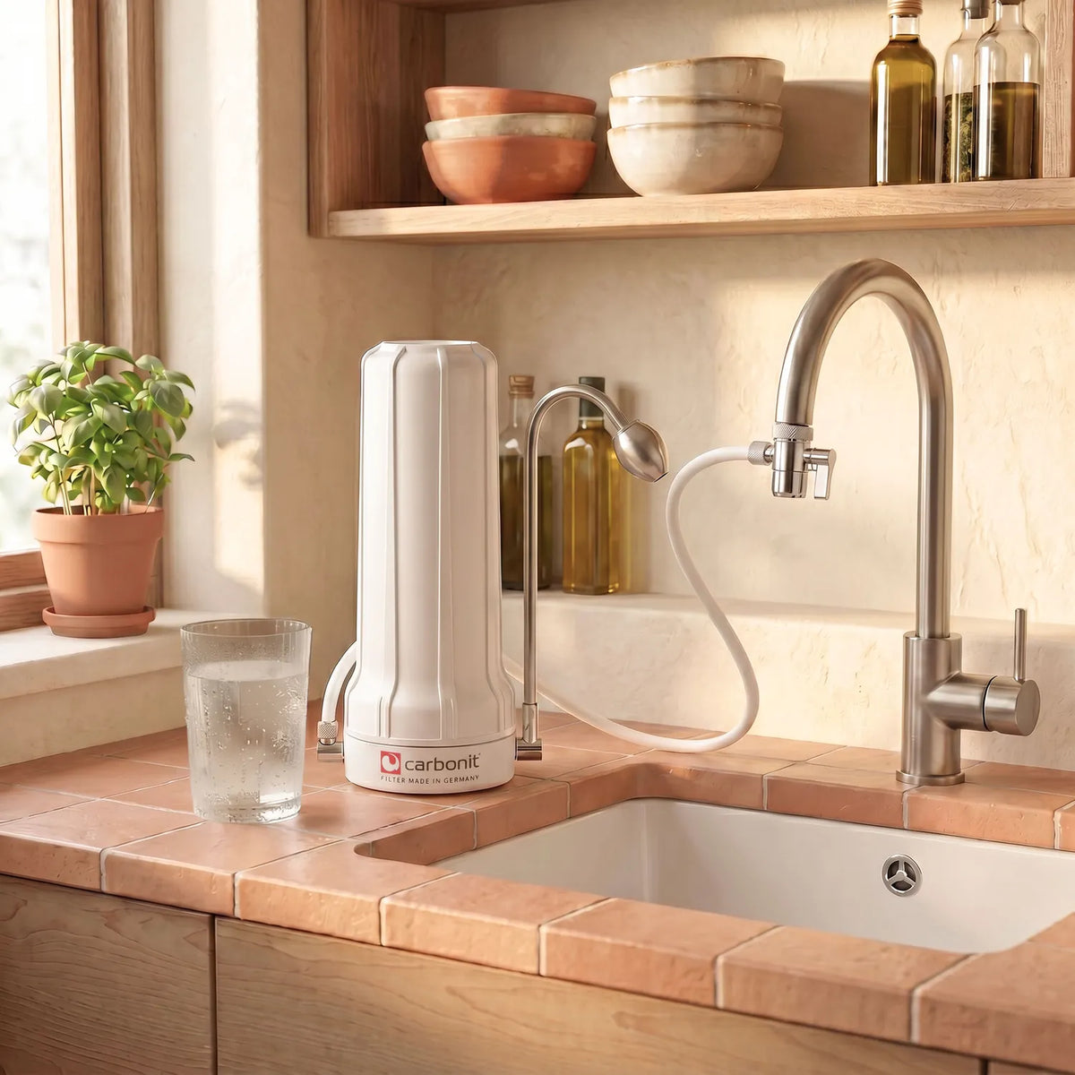 Carbonit Sanuno Vital Auftischfilter weiß in heller Küche – Lifestyle-Aufnahme mit Glas Wasser und Küchenutensilien